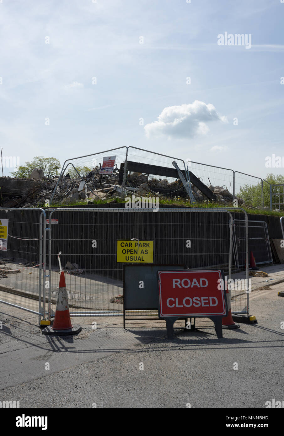 Steel security fencing with road closed sign and car park open as usual in front of demolition