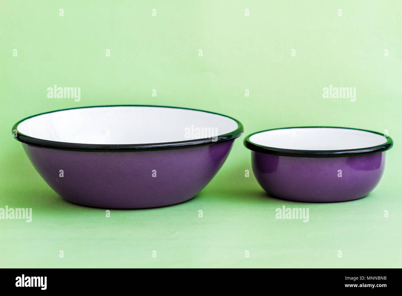 Purple enamel bowls on green background Stock Photo