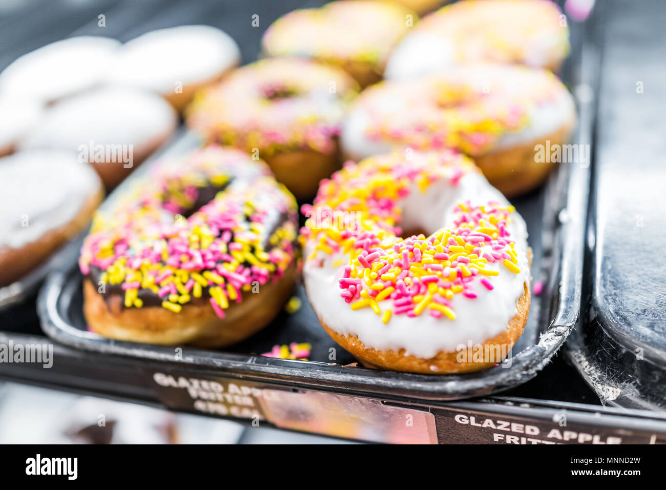Chocolate and white icing donuts with pink sprinkles closeup on bakery ...