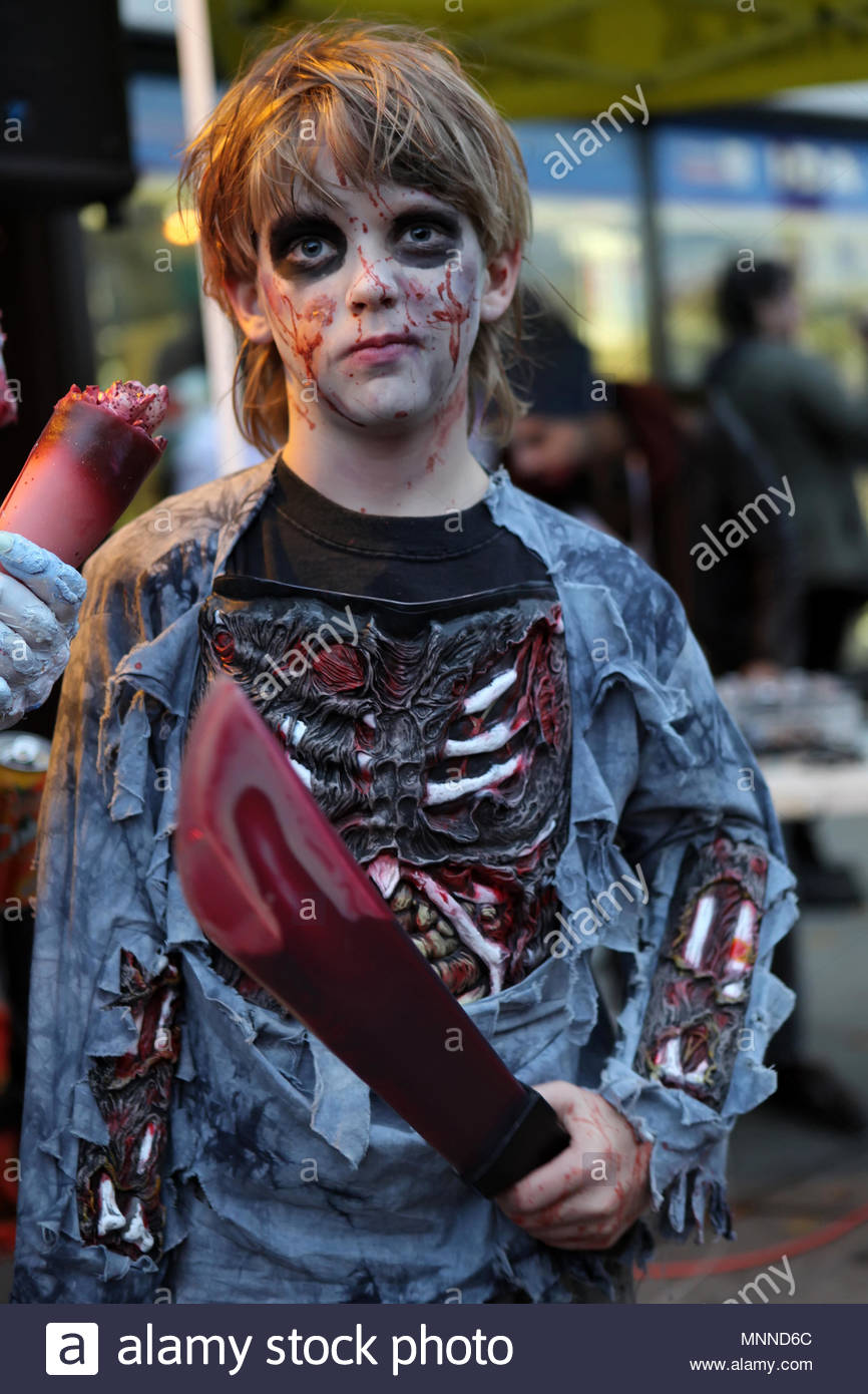 A boy in a Halloween costume with fake blood on his face and ...