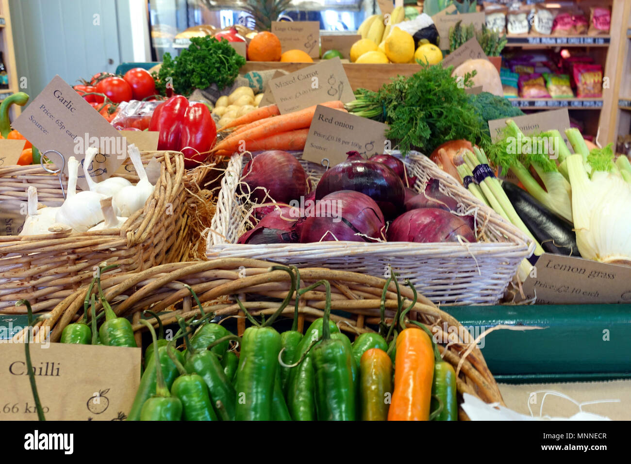 Brightly coloured selection of healthy organic vegetables in wicker baskets, including chilli, garlic, red onion,pepper, tomato and carrot. Stock Photo