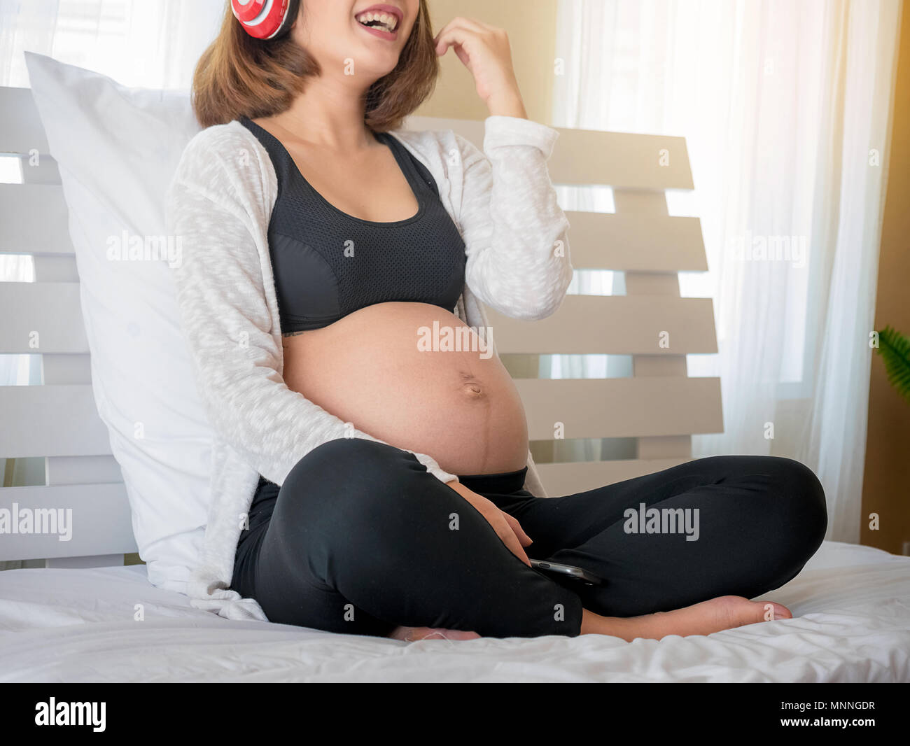 Happy pregnant woman listening to music in the bed room Stock Photo - Alamy