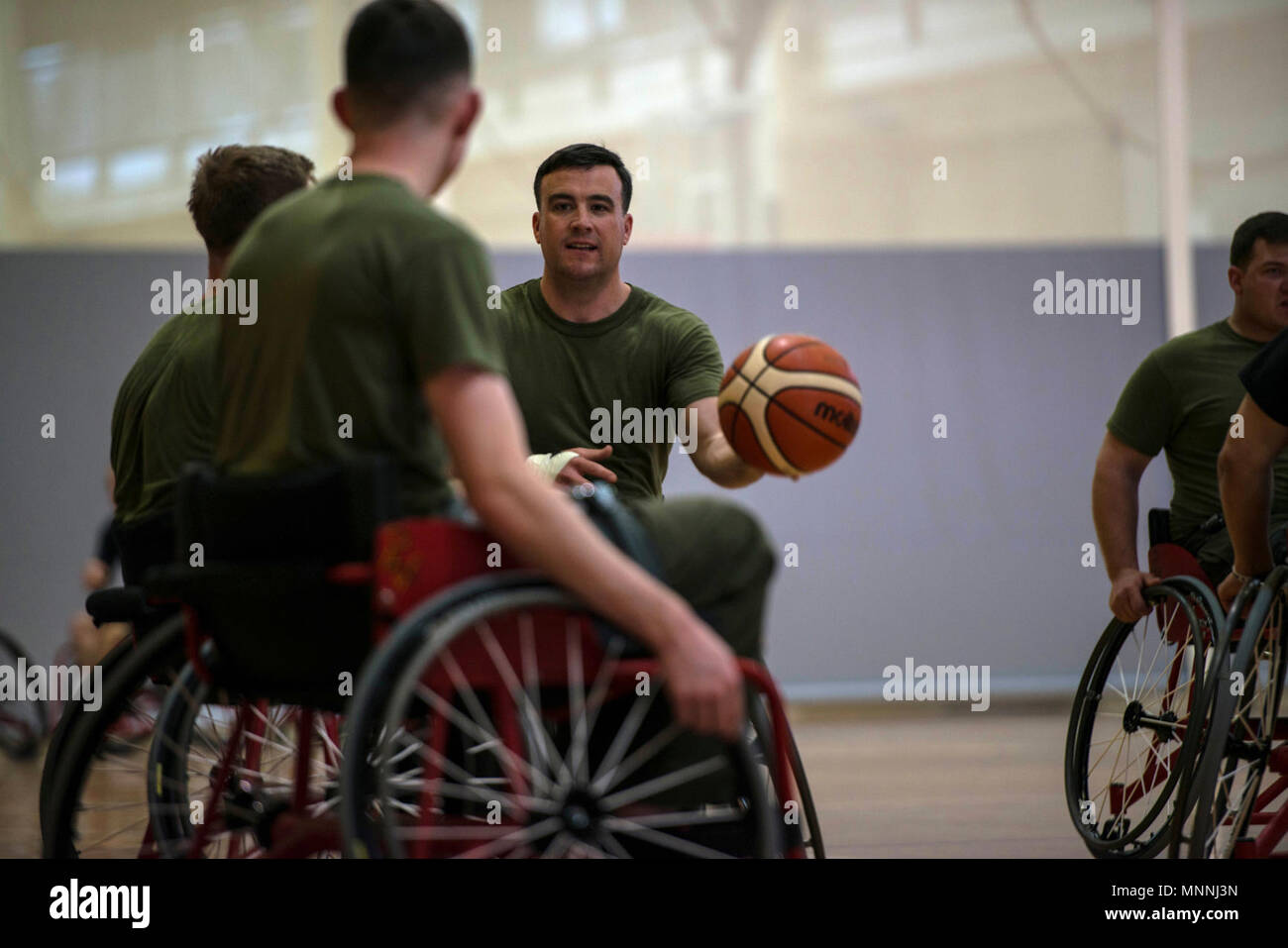 A Wounded Warrior Battalion-East Marine passes to a teammate during a 2018 Marine Corps Trials wheelchair basketball practice at Marine Corps Base Camp Lejeune, N.C., March 15, 2018. The Marine Corps Trials promotes recovery and rehabilitation through adaptive sport participation and develops camaraderie among recovering service members (RSMs) and veterans. It is an opportunity for RSMs to demonstrate their achievements and serves as the primary venue to select Marine Corps participants for the DoD Warrior Games. Stock Photo