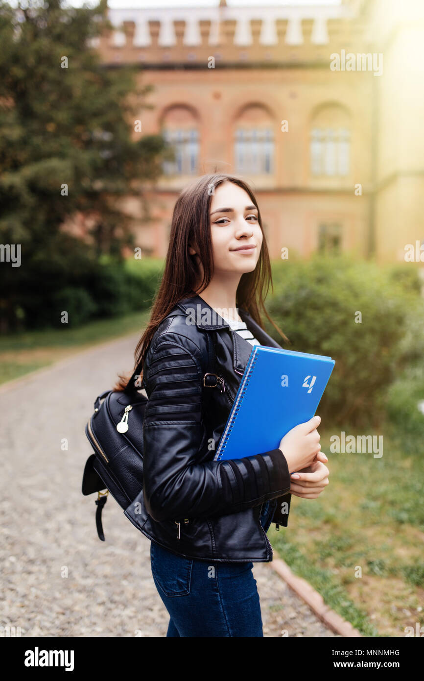 Happy cute young woman student with backpack holding books and walking ...