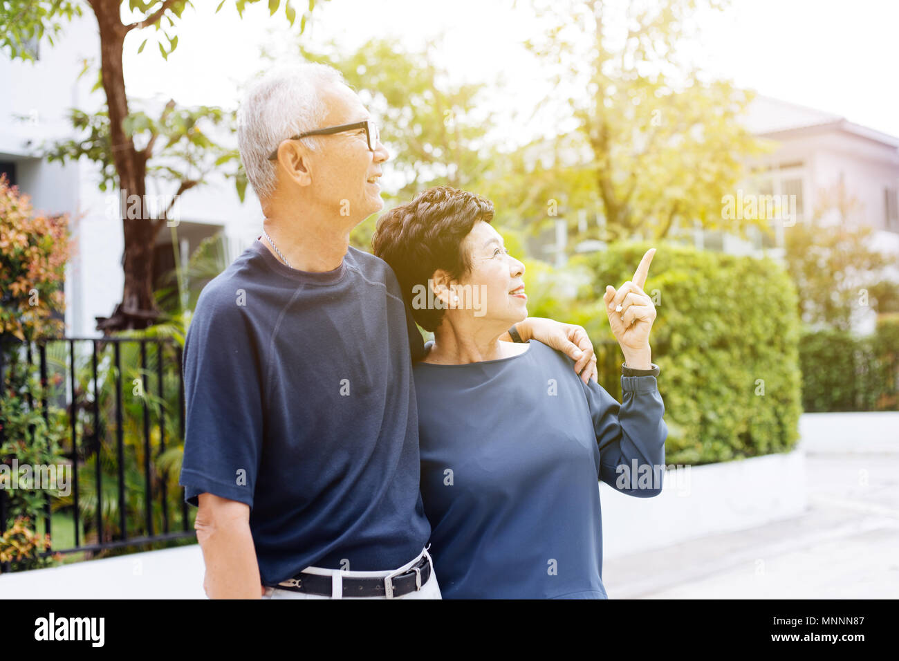 Happy senior Asian couple walking and pointing in outdoor park and ...