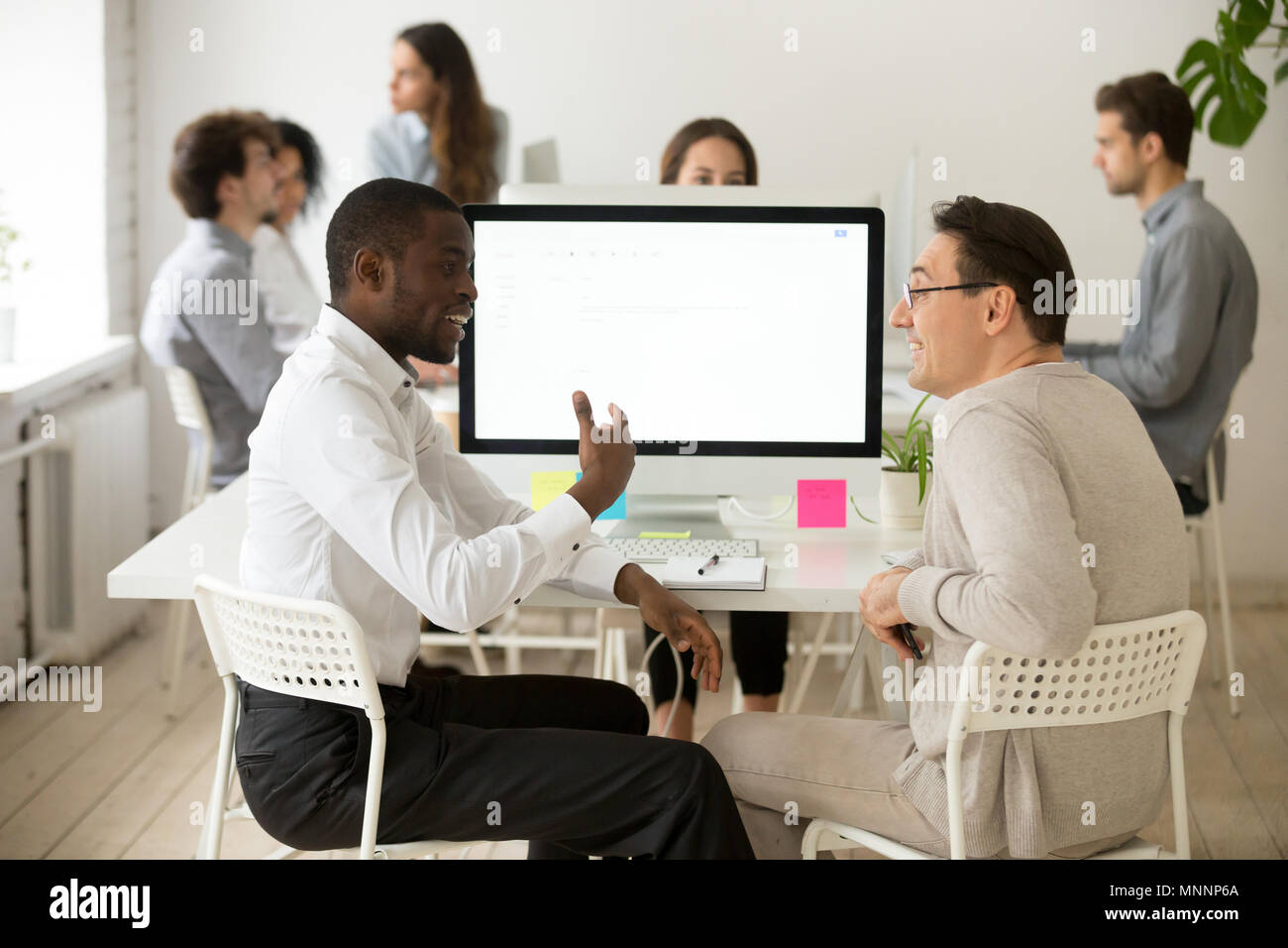 Friendly smiling diverse male colleagues having pleasant convers Stock Photo