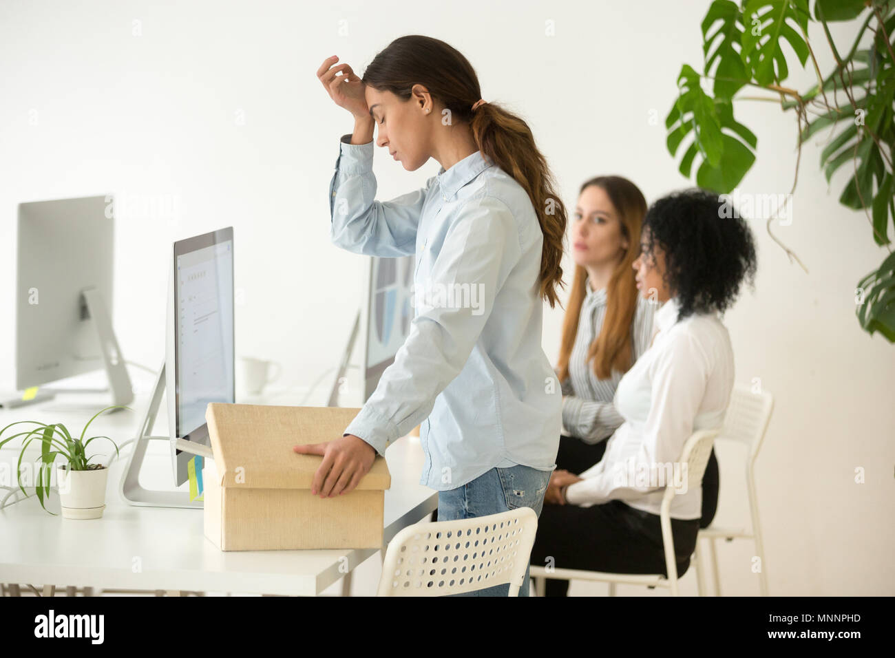 Upset fired dismissed young woman employee packing box leaving w Stock Photo