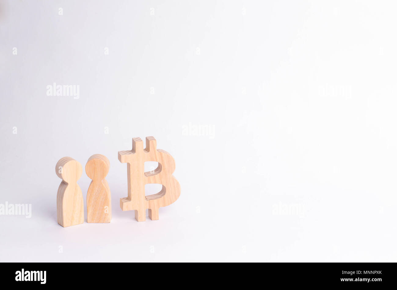 Wooden figures of people are standing near a bitcoin on a white ...