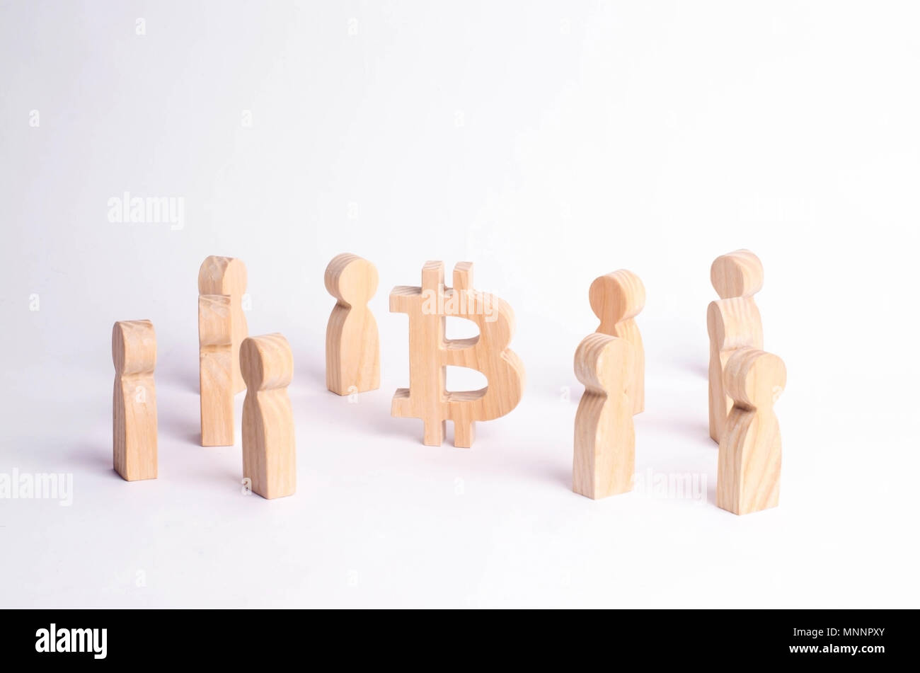 Wooden figures of people are standing near a bitcoin on a white ...