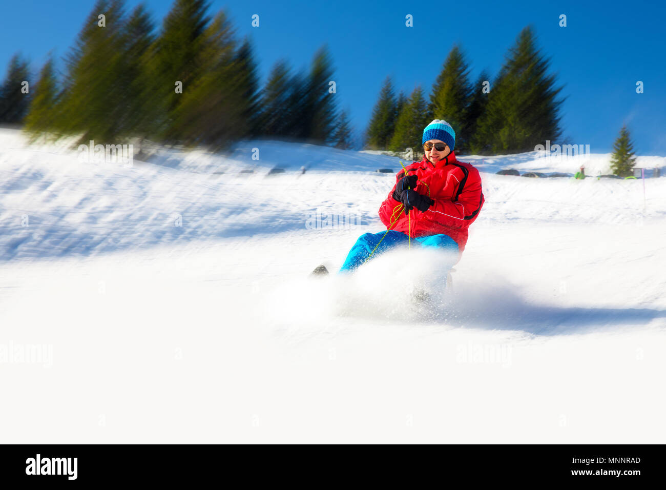 Young attractive man sledding in Alps during winter holiday. Stock Photo