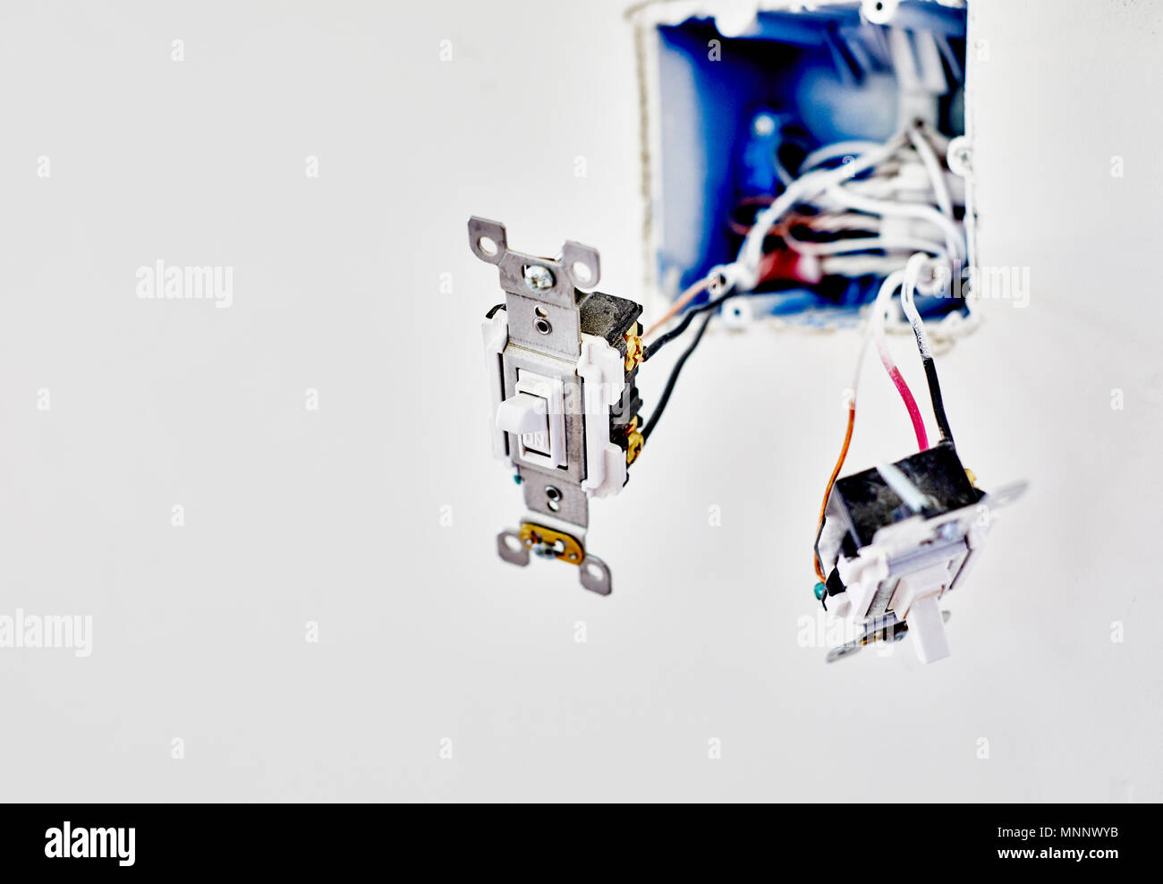 Two new light switches hanging from wires while being installed in new