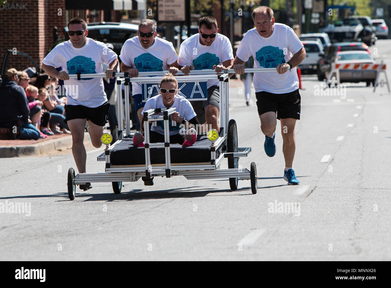 A team pushes a bed on wheels in a bed race charity fundraiser event on