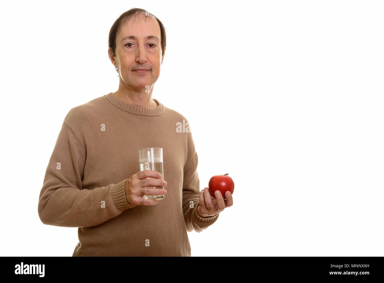 Studio shot of mature man holding glass of water and red apple Stock Photo