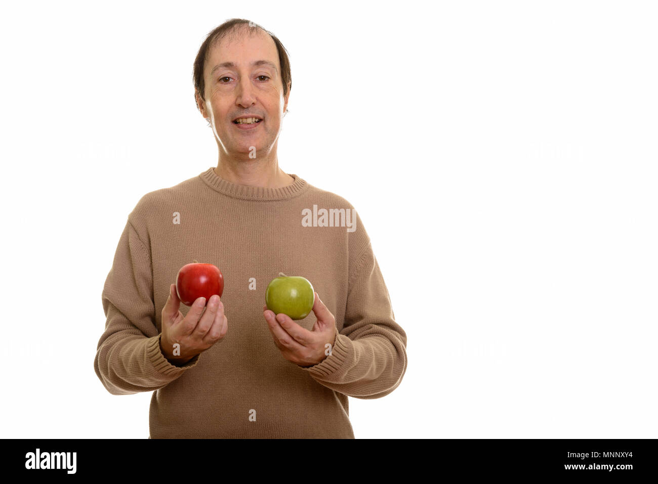 Studio shot of happy mature man smiling while holding red and gr Stock Photo