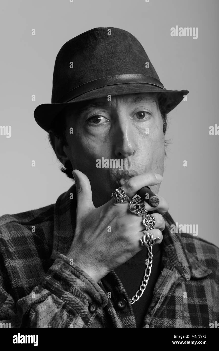Face of mature gangster man smoking cigar in black and white Stock Photo