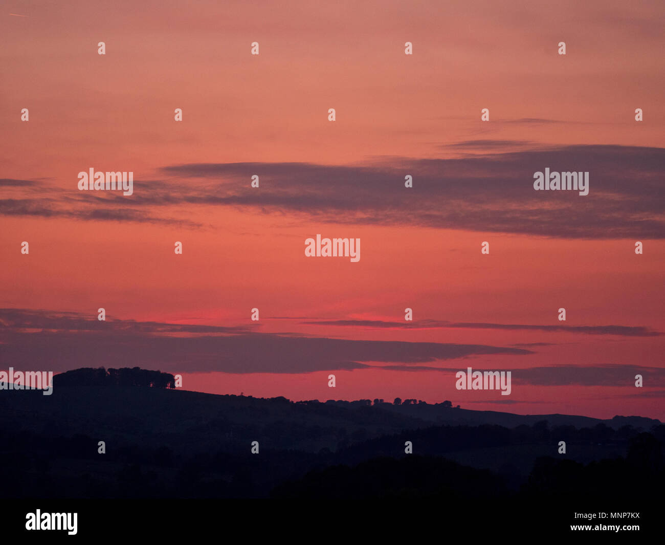Peak District, Derbyshire, UK. 18th May, 2018. UK Weather: spectacular sunset over the ancient woods Hazleton Clump Cairn near Thorpe taken from Ashbourne Derbyshire, Peak District National Park Credit: Doug Blane/Alamy Live News Stock Photo