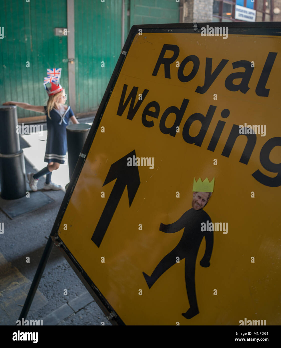 Windsor, UK, 19 May 2018. A young girl next to a road sign for the Royal Wedding of Harry and Meghan in Windsor, London, on which someone has placed a sticker with the head of Prince Harry. Photo date: Saturday, May 19, 2018. Photo: Roger Garfield/Alamy Stock Photo