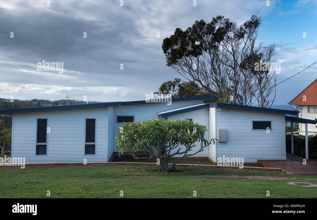 An older 1950s weatherboard cottage that has now been completely clad, walls and roof in Colourbond powder coated steel with new windows. Stock Photo