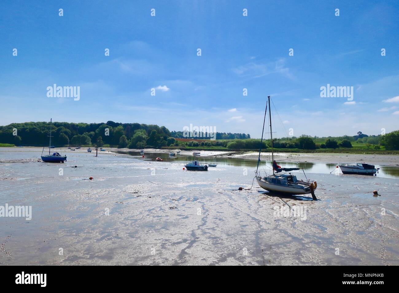 Boats in the mud at low tide.  River Deben, Woodbridge, Suffolk.May 2018. Stock Photo