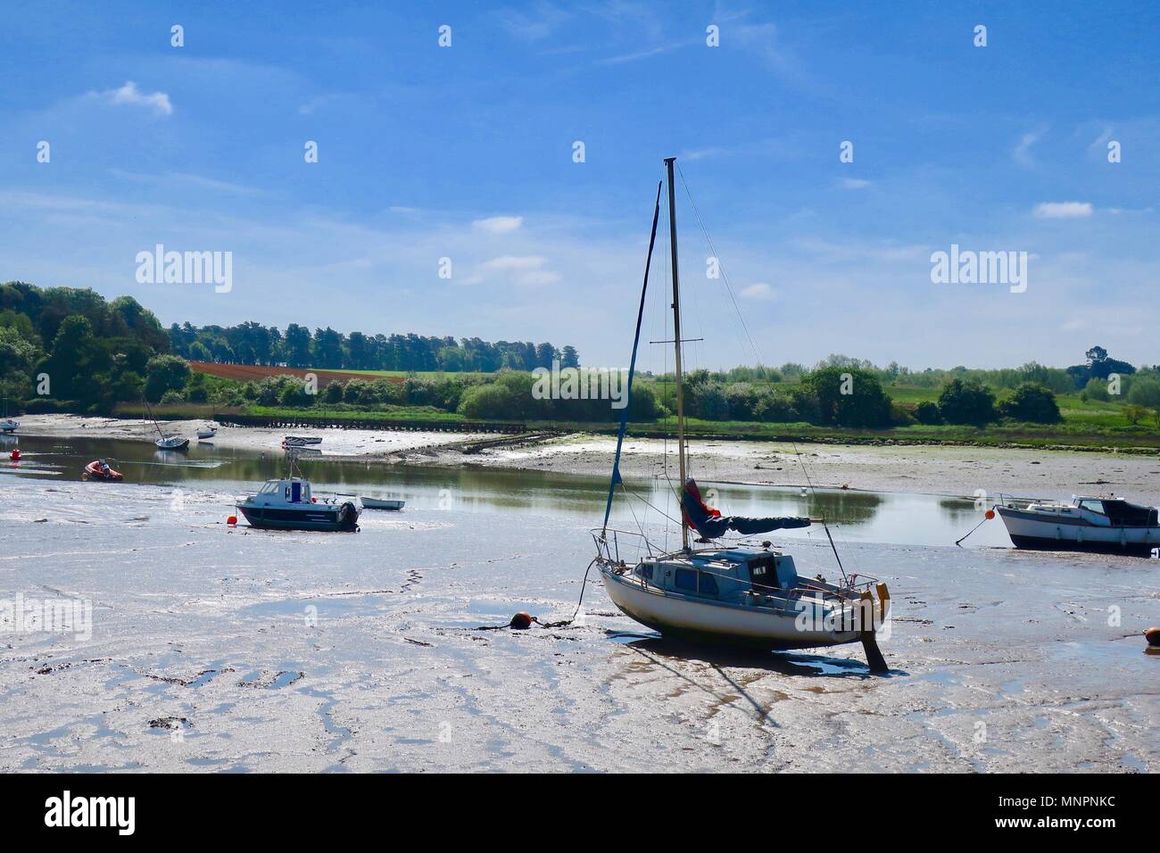 Boats in the mud at low tide.  River Deben, Woodbridge, Suffolk.May 2018. Stock Photo