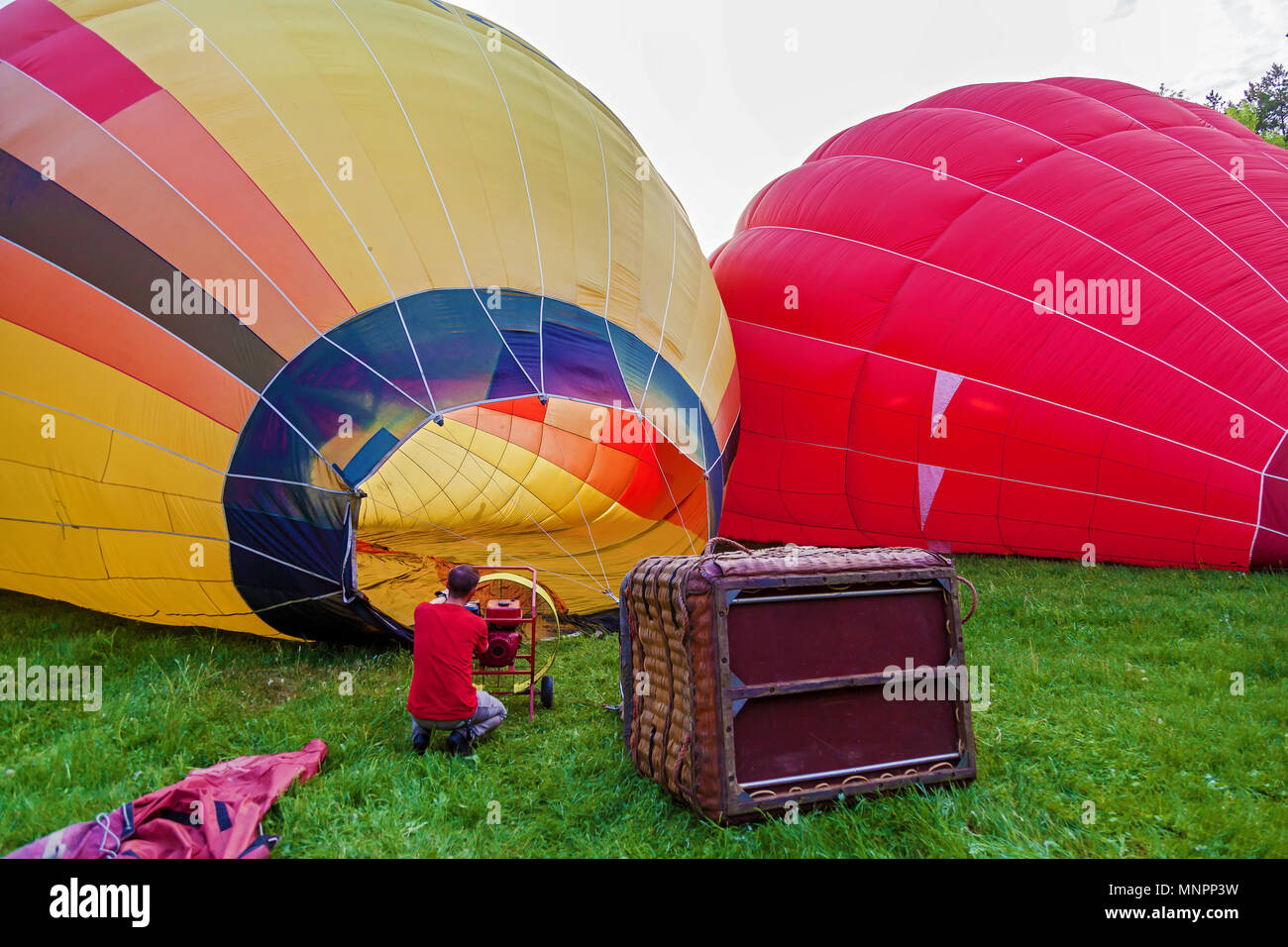 A balloon with a basket lies on the ground, equipment for filling the