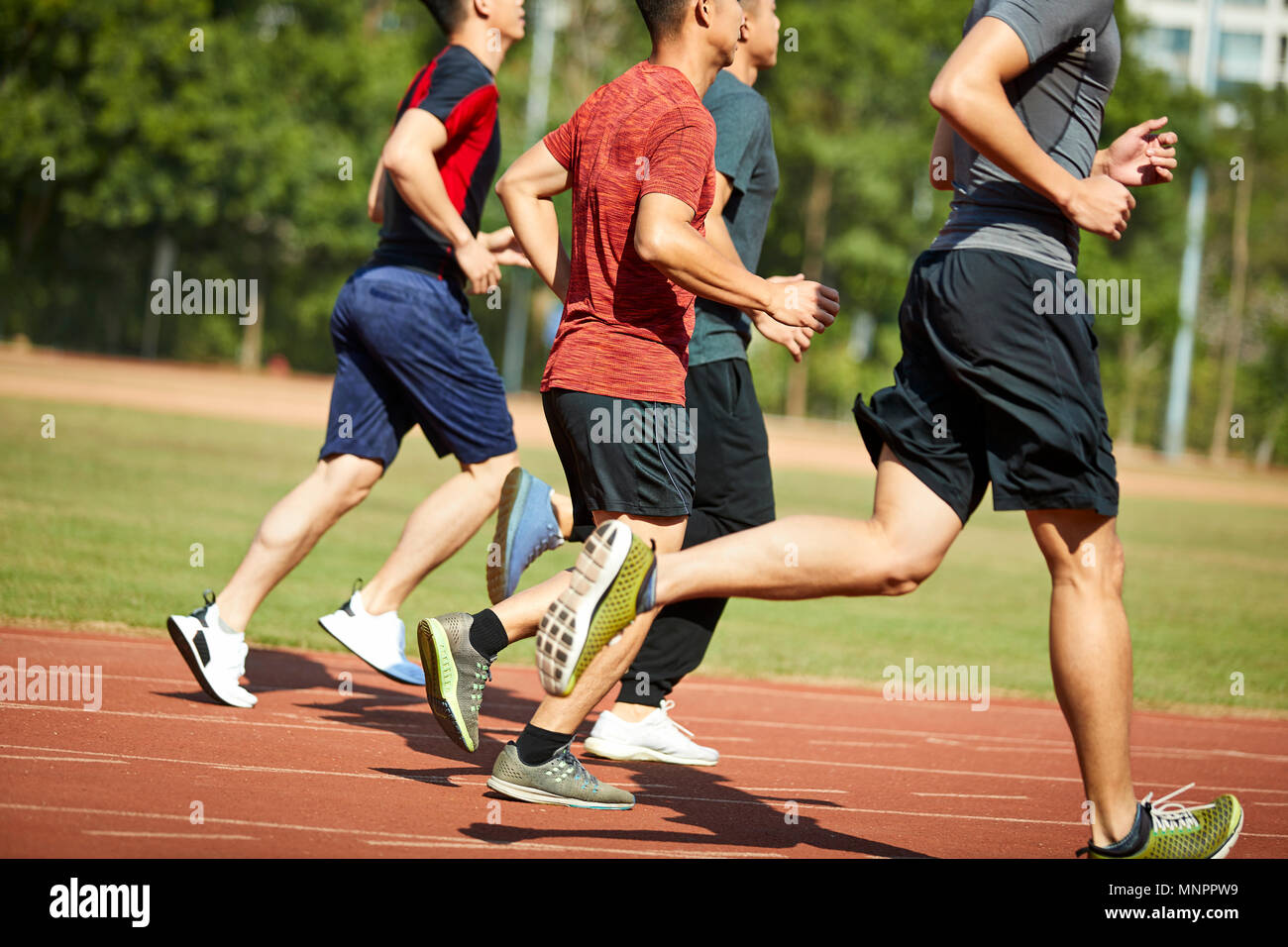 four asian young adults training running on track. Stock Photo