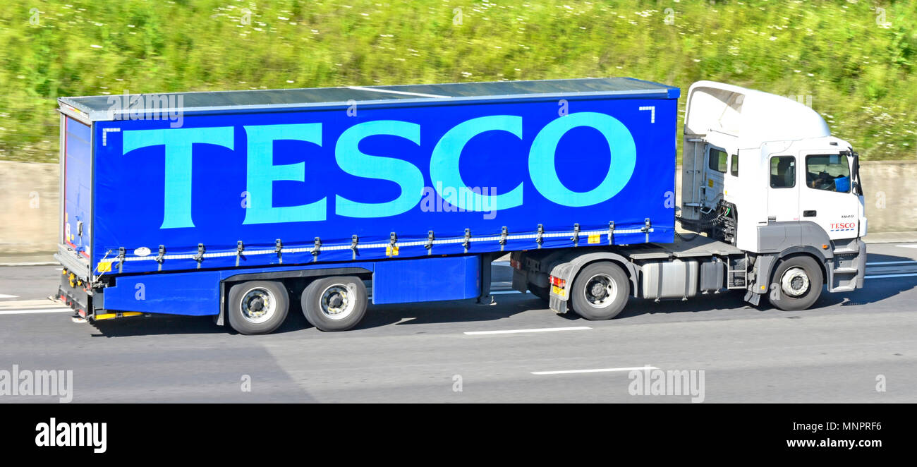 Side view of hgv supermarket food supply chain store grocery delivery lorry truck with trailer advertising Tesco business name driving on UK motorway Stock Photo