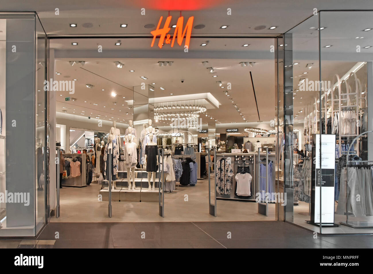 Shopping Mall early morning entrance & interior design of H&M clothing store mannequin displays & shoppers amongst racks Westfield Stratford London UK Stock Photo