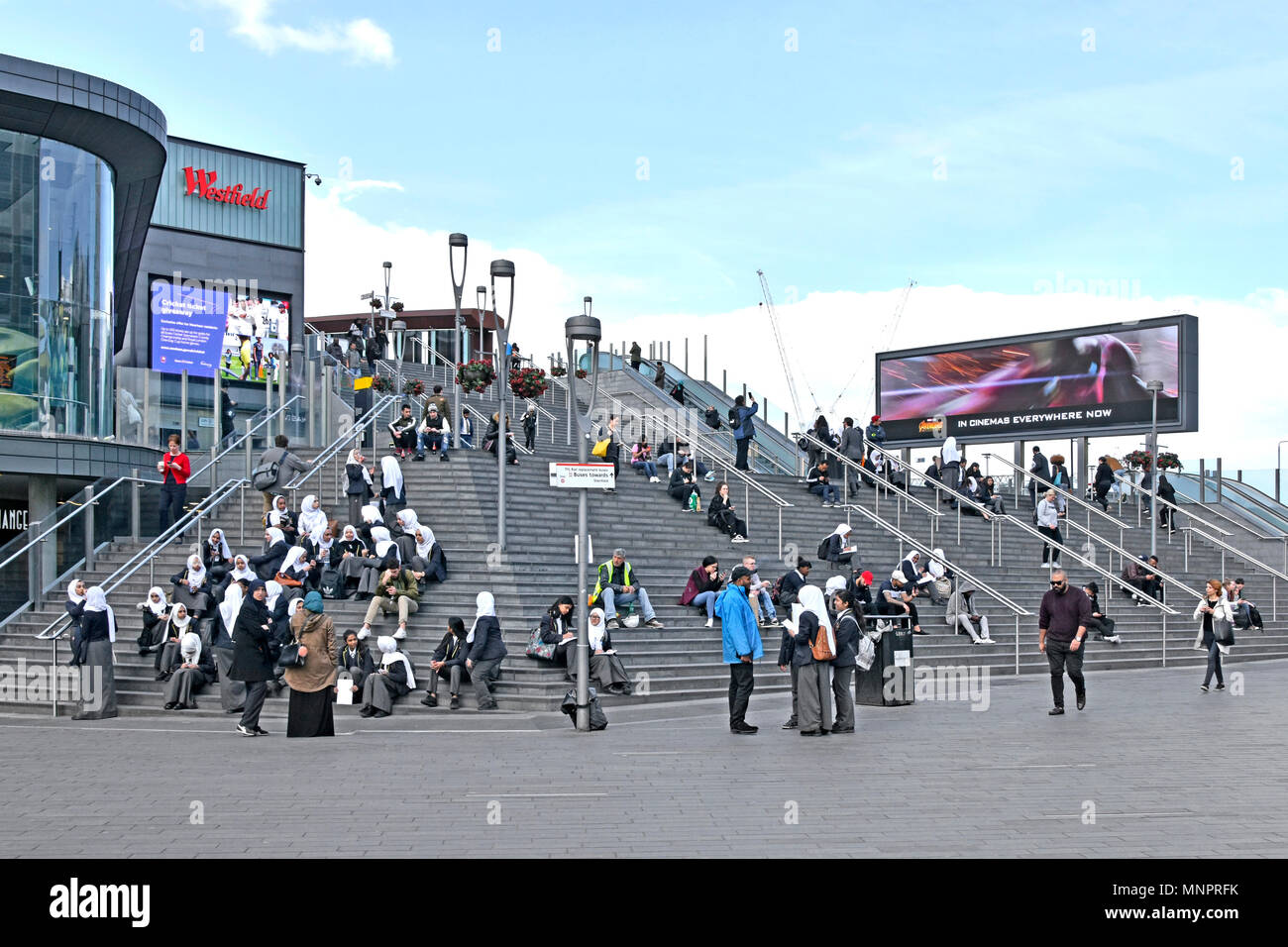 Girl school children in uniform many wearing hijab with staff on steps up to Westfield shopping centre multicultural Stratford Newham East London UK Stock Photo