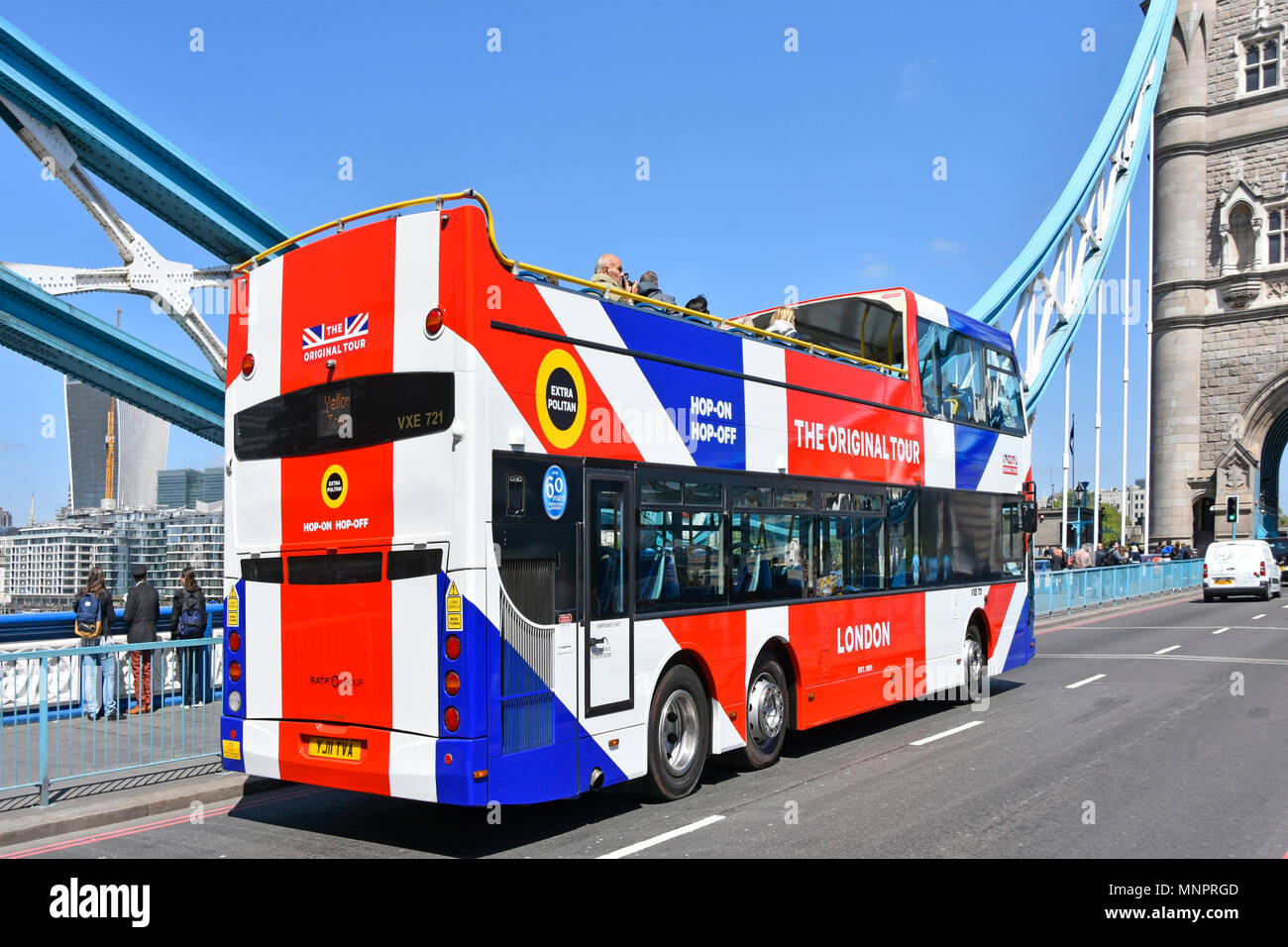 London street scene tourists on colourful red white & blue double decker open top city tourism sightseeing tour bus at Tower Bridge London England UK Stock Photo