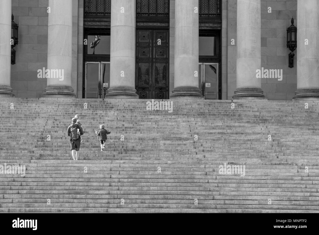 Olympia, Washington / USA - May 5, 2018: A father and his children walk up the steps of the Washington State Capitol building carrying balloons on a b Stock Photo