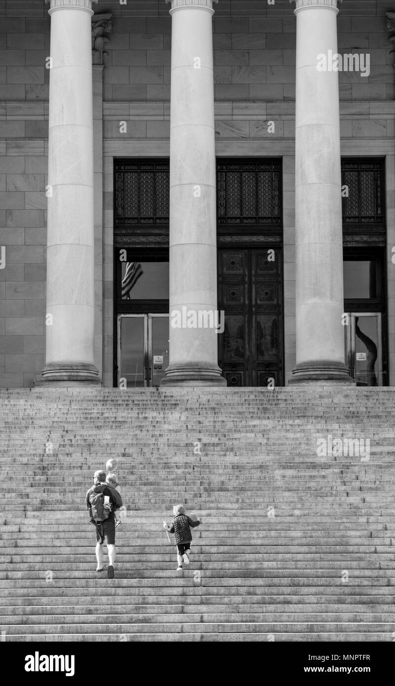 Olympia, Washington / USA - May 5, 2018: A father and his children walk up the steps of the Washington State Capitol building carrying balloons on a b Stock Photo