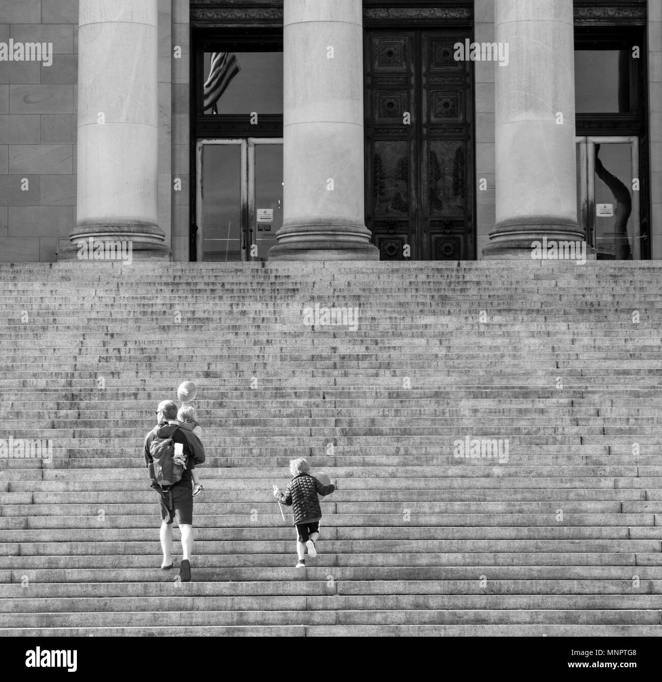 Olympia, Washington / USA - May 5, 2018: A father and his children walk up the steps of the Washington State Capitol building carrying balloons on a b Stock Photo