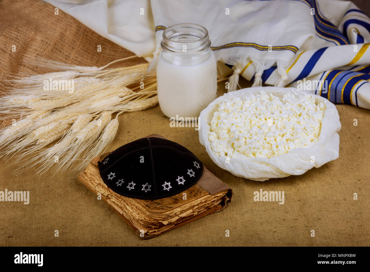 Dairy products on wheat field table torah, Symbols of jewish holiday - Shavuot Stock Photo