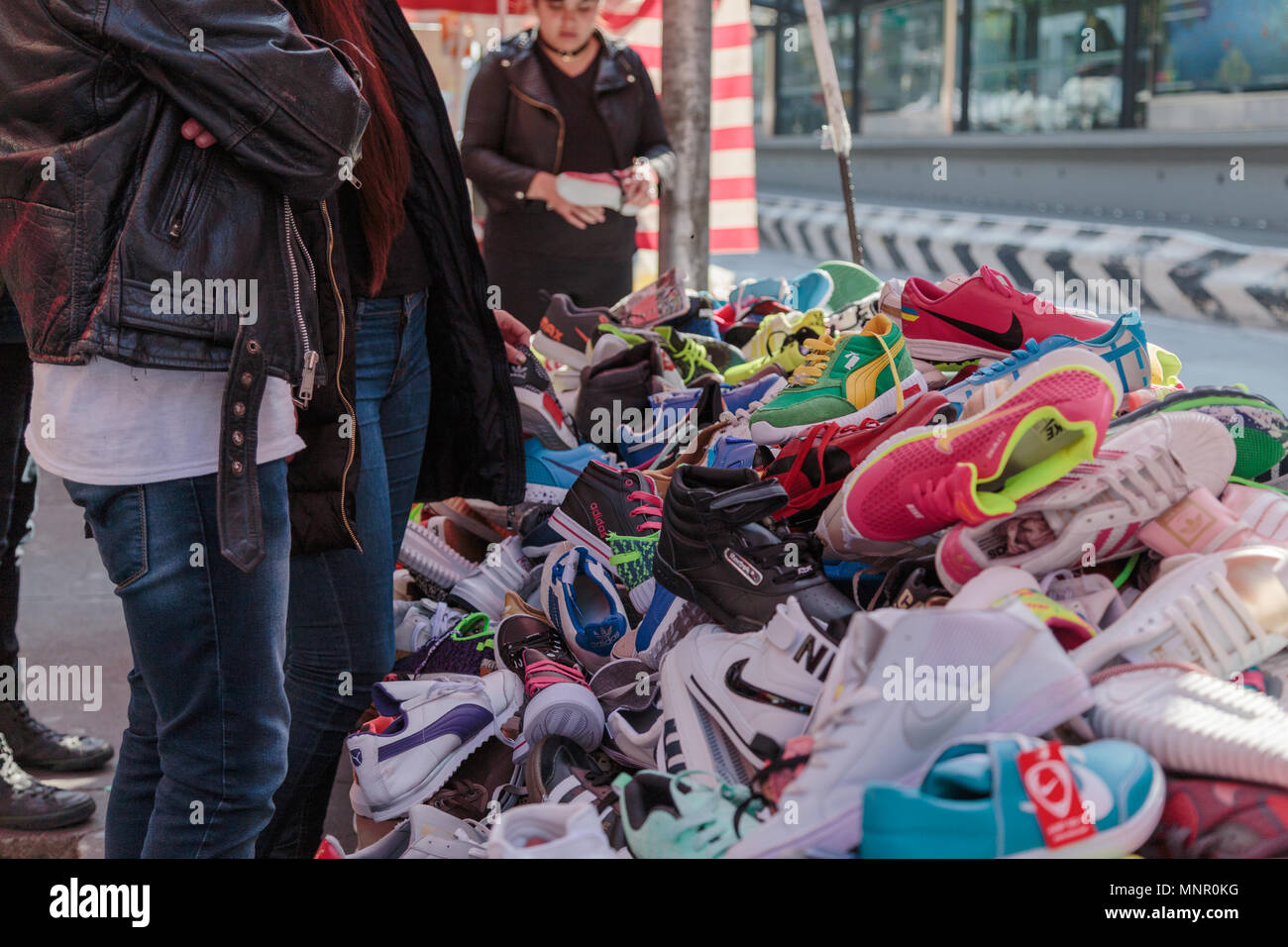 The potensial customers look at the randomly piled up shoes by the vender at Park Alameda Central,, Mexico City, Mexico. Stock Photo