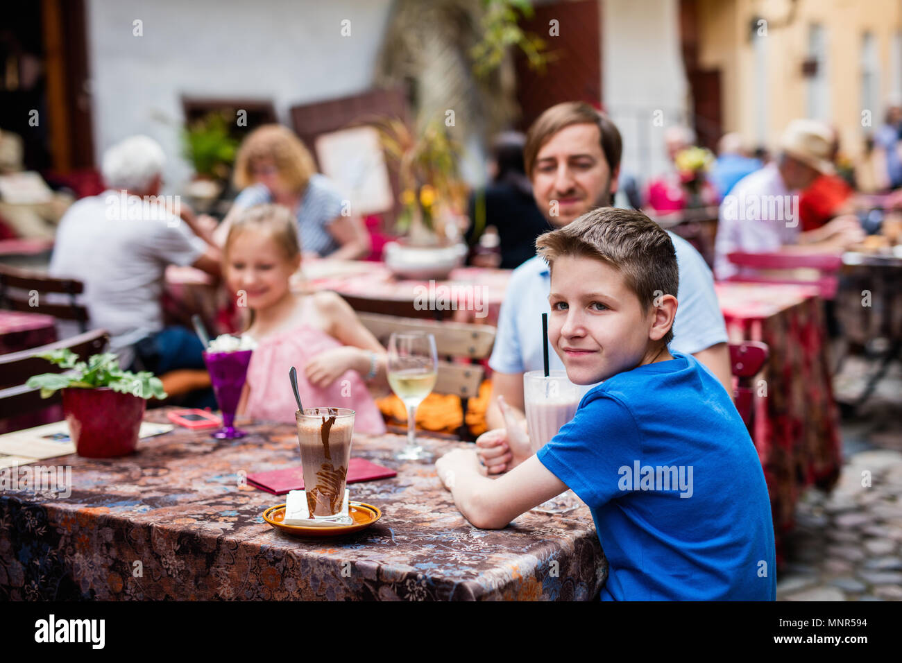Father and his kids at outdoor cafe on summer day Stock Photo