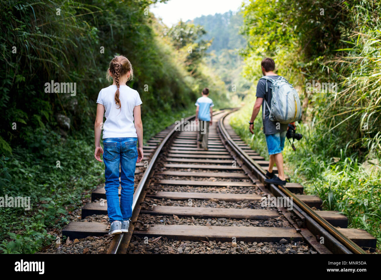 Family of father and two kids walking along train tracks in Sri Lanka