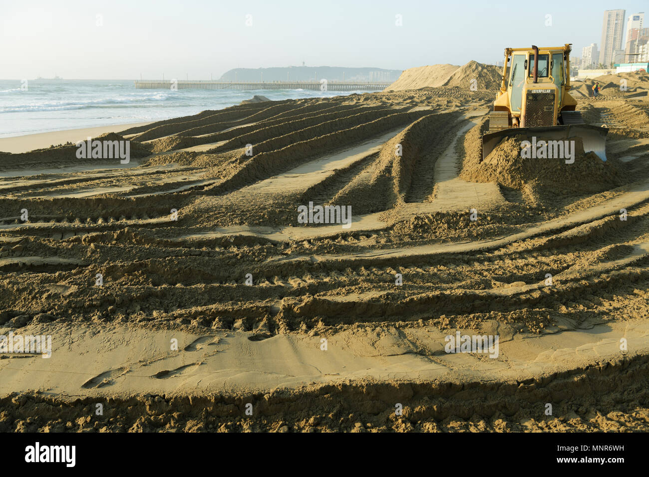 Durban, KwaZulu-Natal, South Africa, yellow bulldozer levelling sand, beach repair project on Golden Mile beachfront, landscape, earth moving Stock Photo