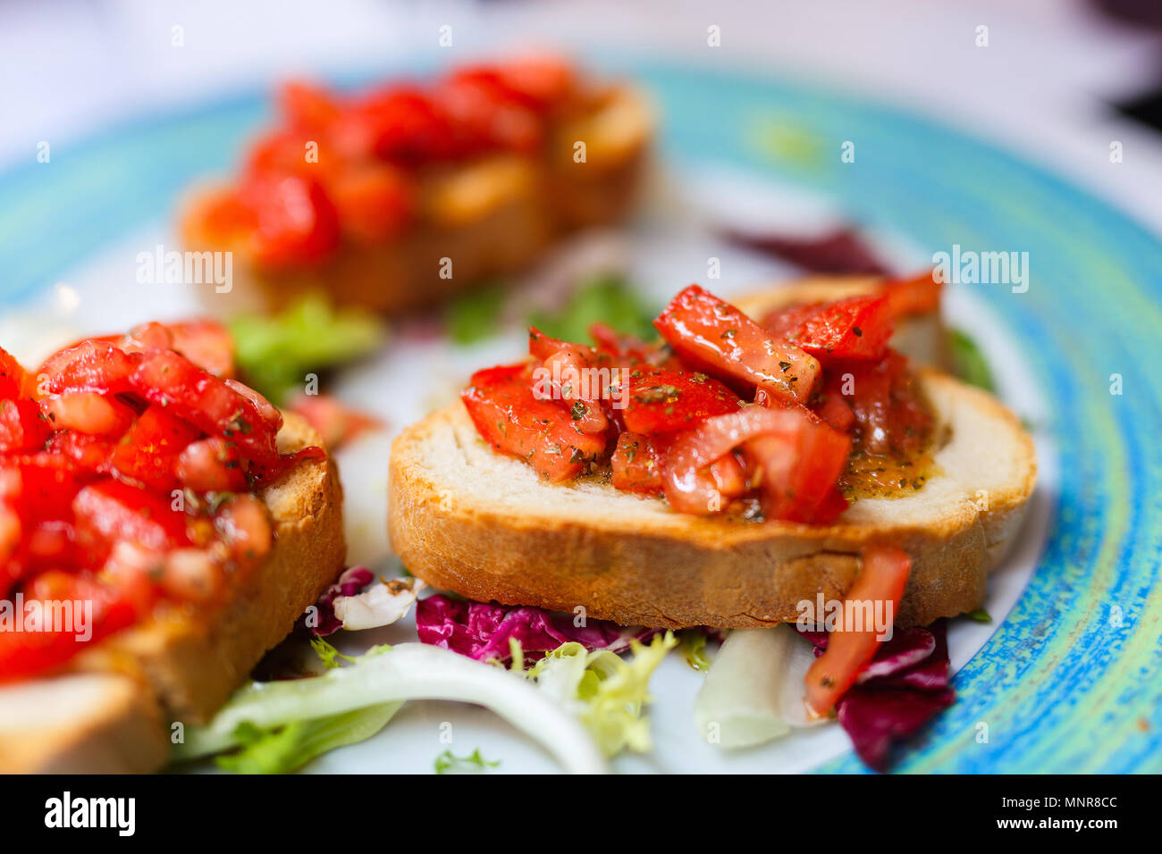 Fresh homemade crispy Italian antipasto bruschetta topped with tomato