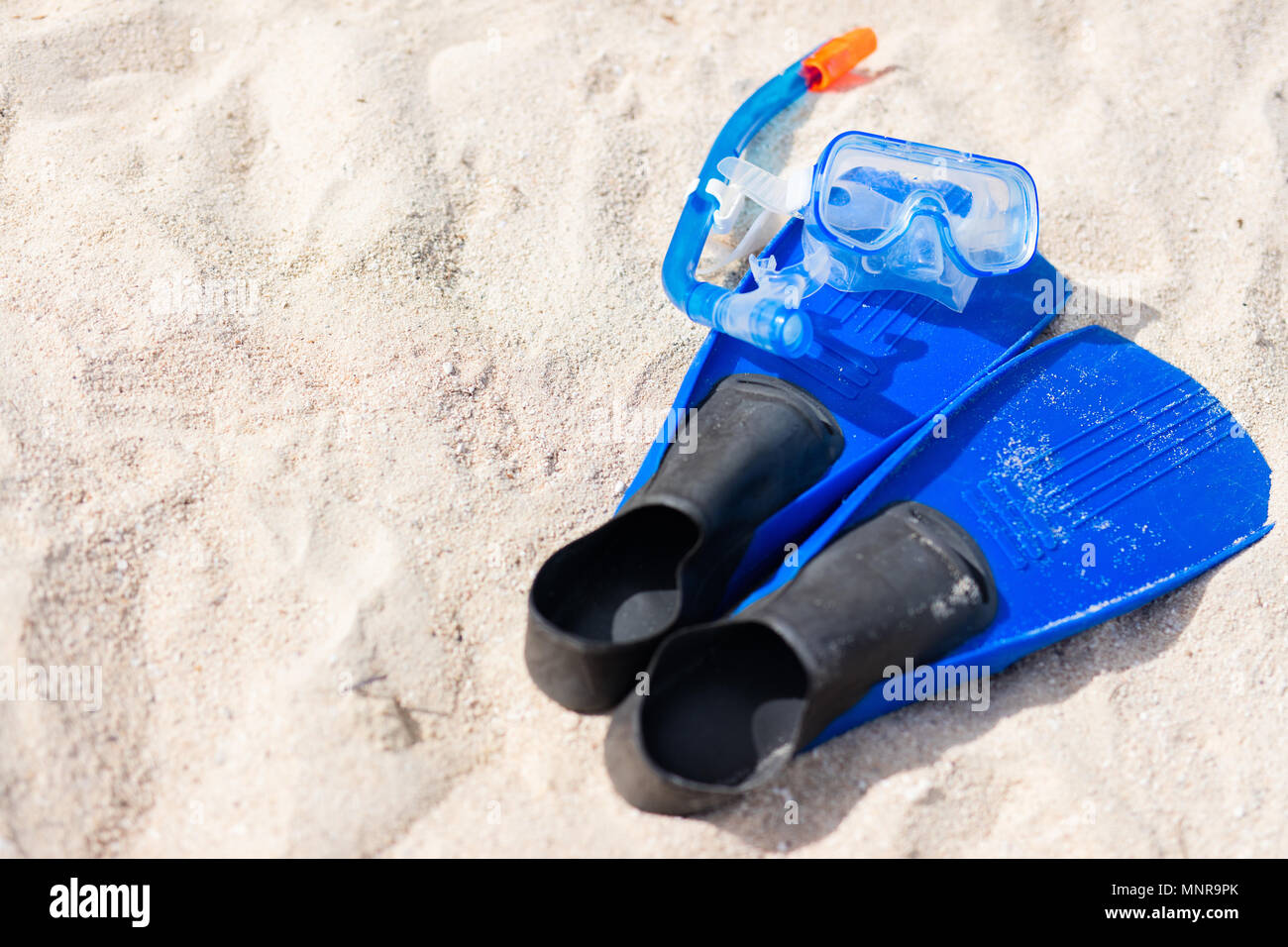 Snorkeling equipment mask, snorkel and fins on sand at beach Stock Photo