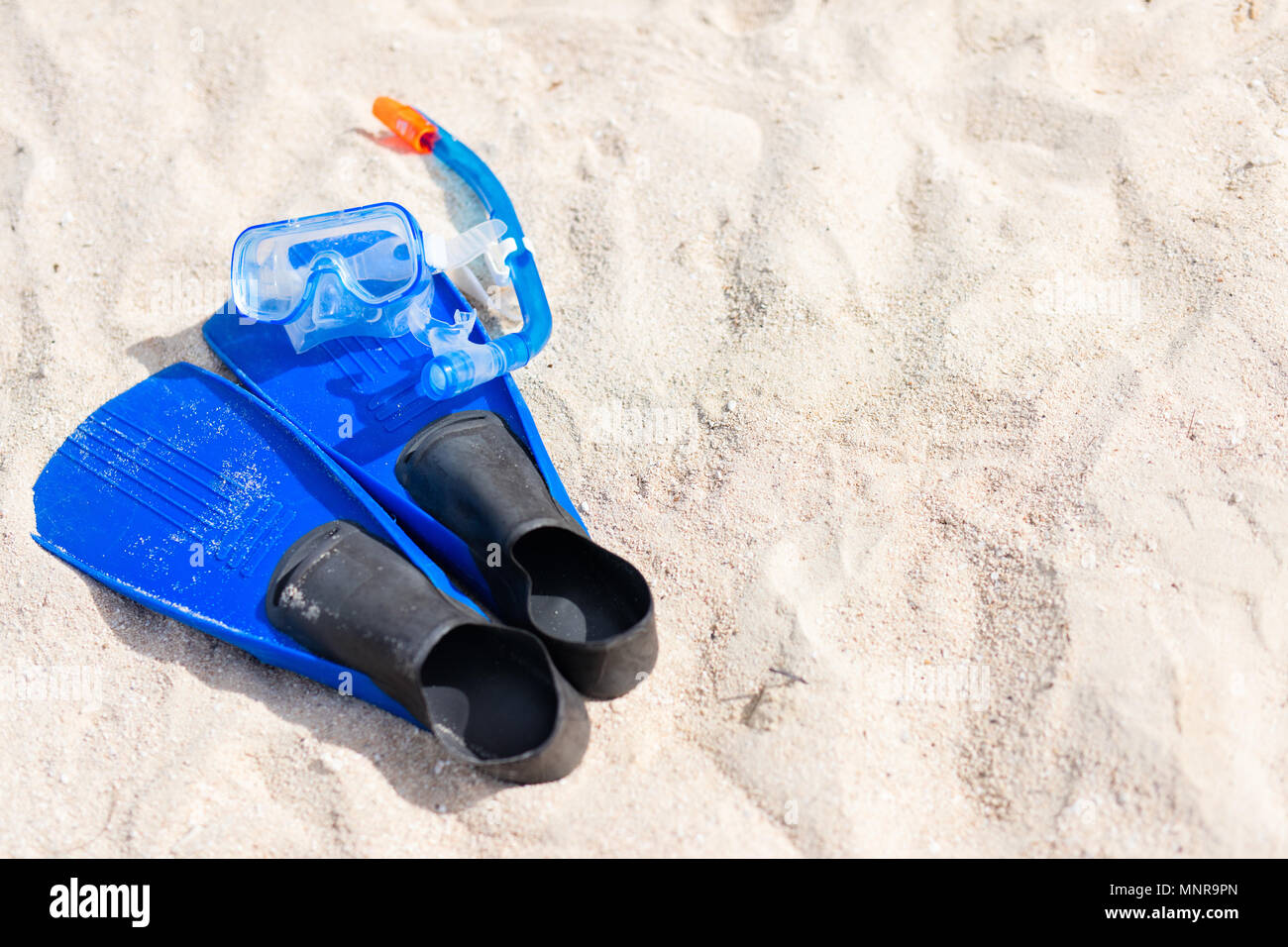 Snorkeling equipment mask, snorkel and fins on sand at beach Stock Photo
