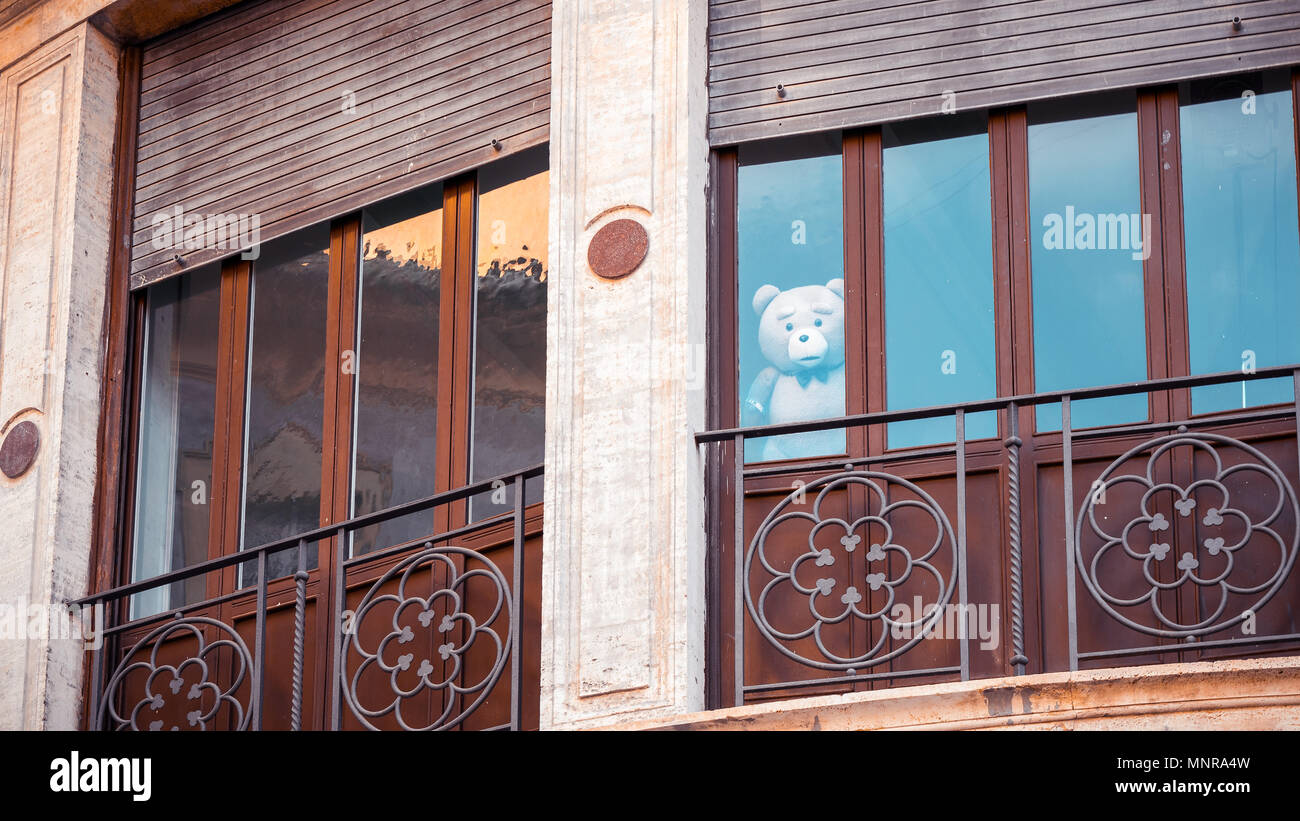 A stuffed teddy bear looks out the window of a building Stock Photo