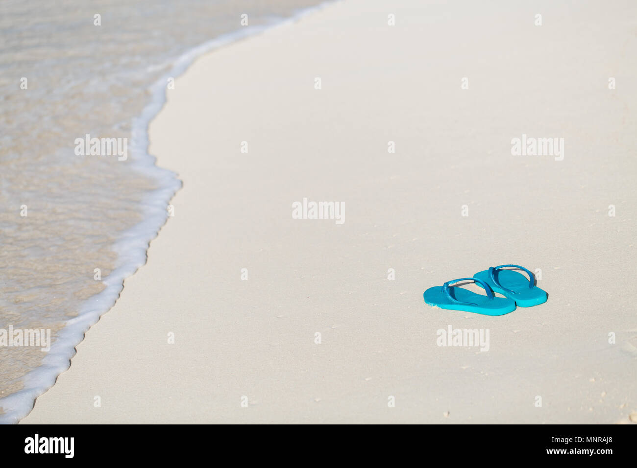 Turquoise flip flops on a tropical beach Stock Photo