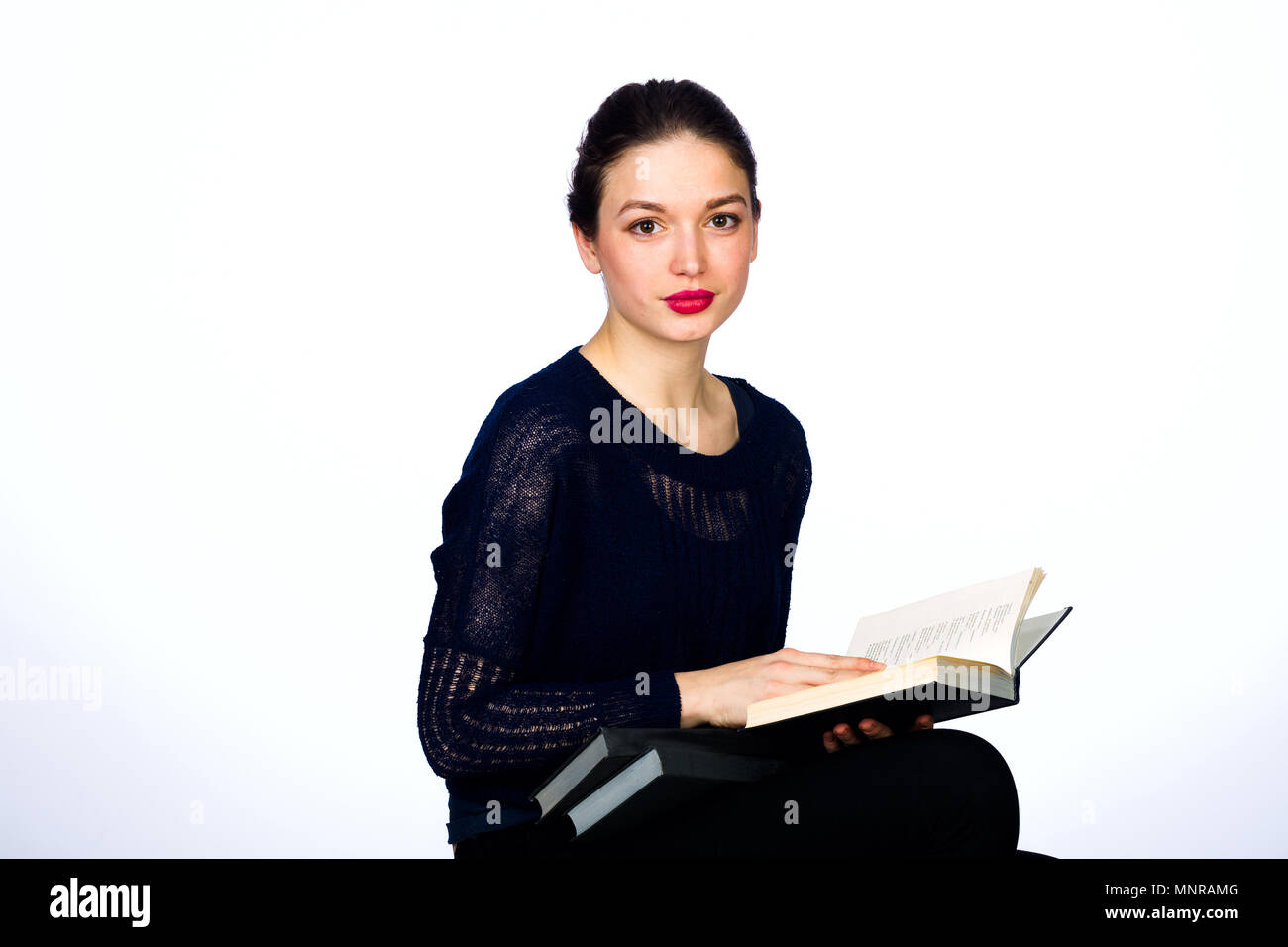 Young emotional girl with books on a white background, studio lighting Stock Photo