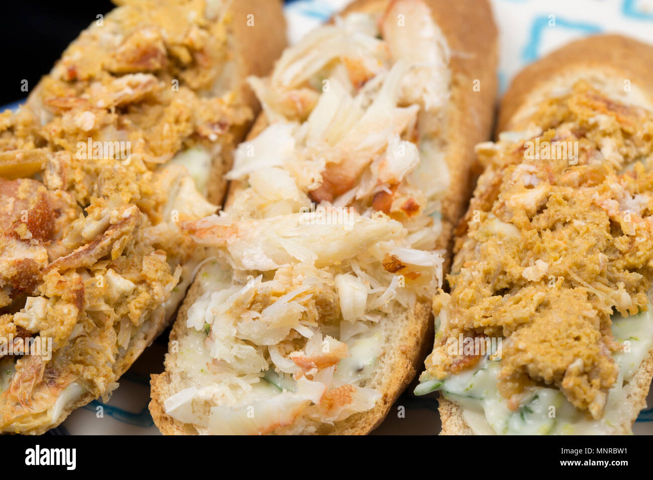Brown and white crab meat from an edible, or brown crab, Cancer pagurus, served on a slice of brown french stick with a dressing of mayonnaise, lime r Stock Photo