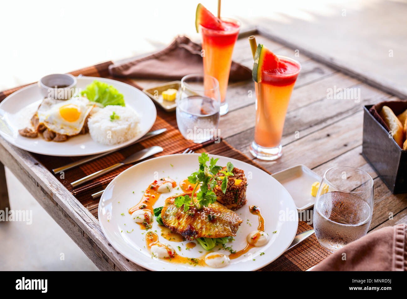Delicious lunch for two in restaurant of fish,  rice,  fried egg and green vegetables Stock Photo
