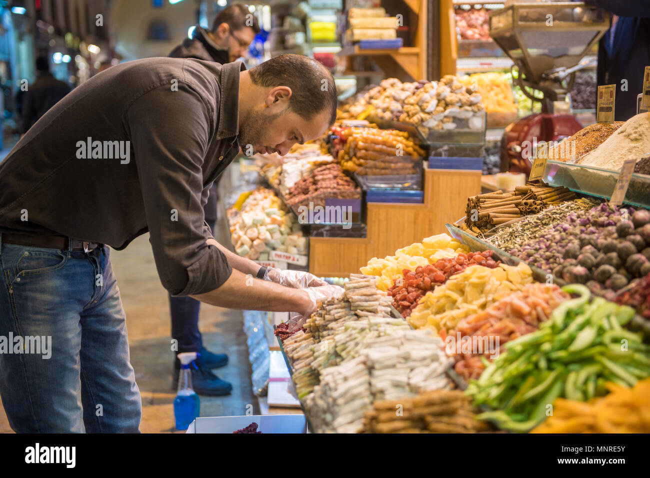 Adult male takes special care to set up market stall in front of spice and sweet shop at Istanbul Spice bazaar in Turkey Stock Photo