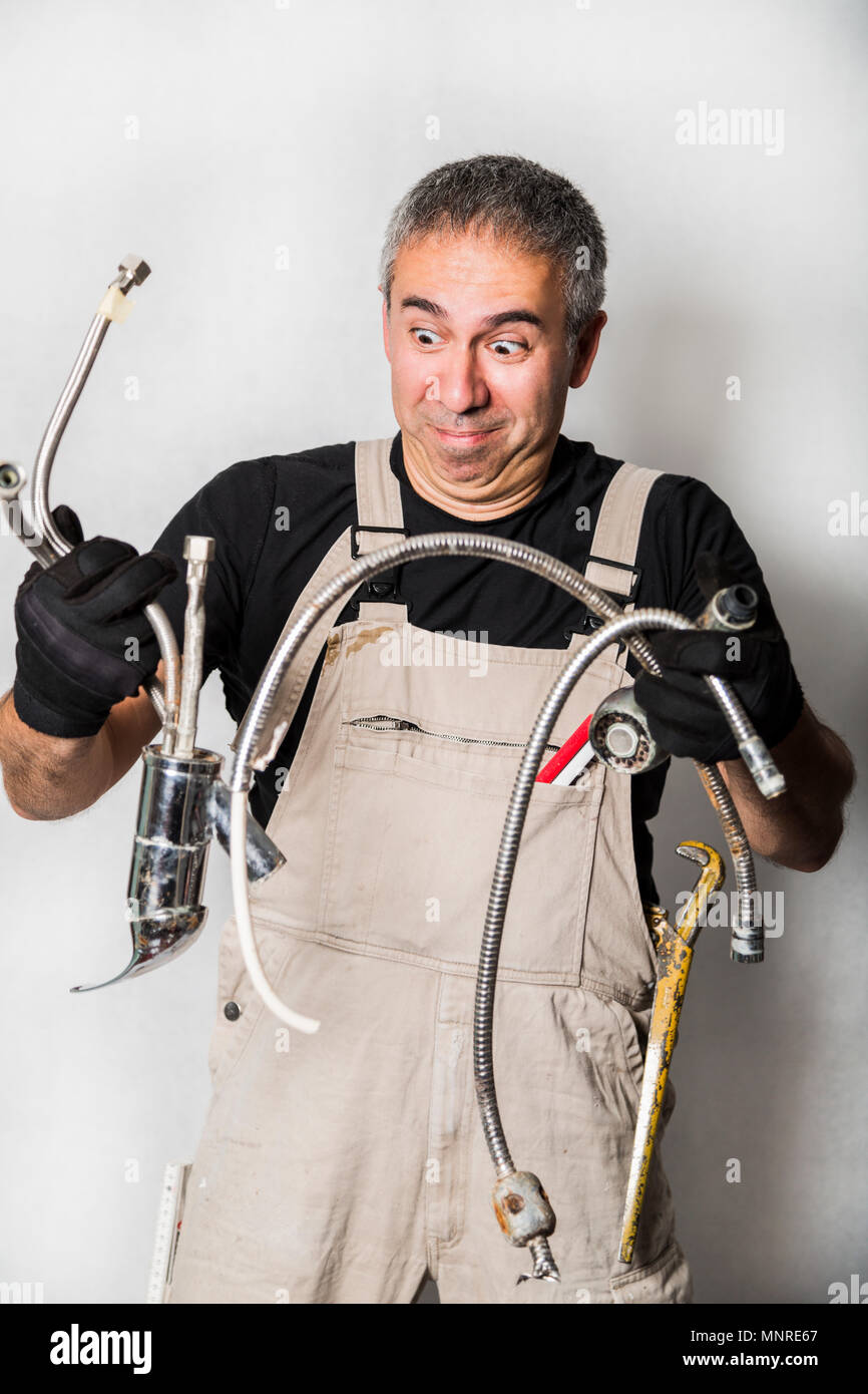 Male man happy funny stupid ugly worker specialist plumber, engineer or constructor in white dirty old shabby working suit, black t-shirt, gloves look Stock Photo