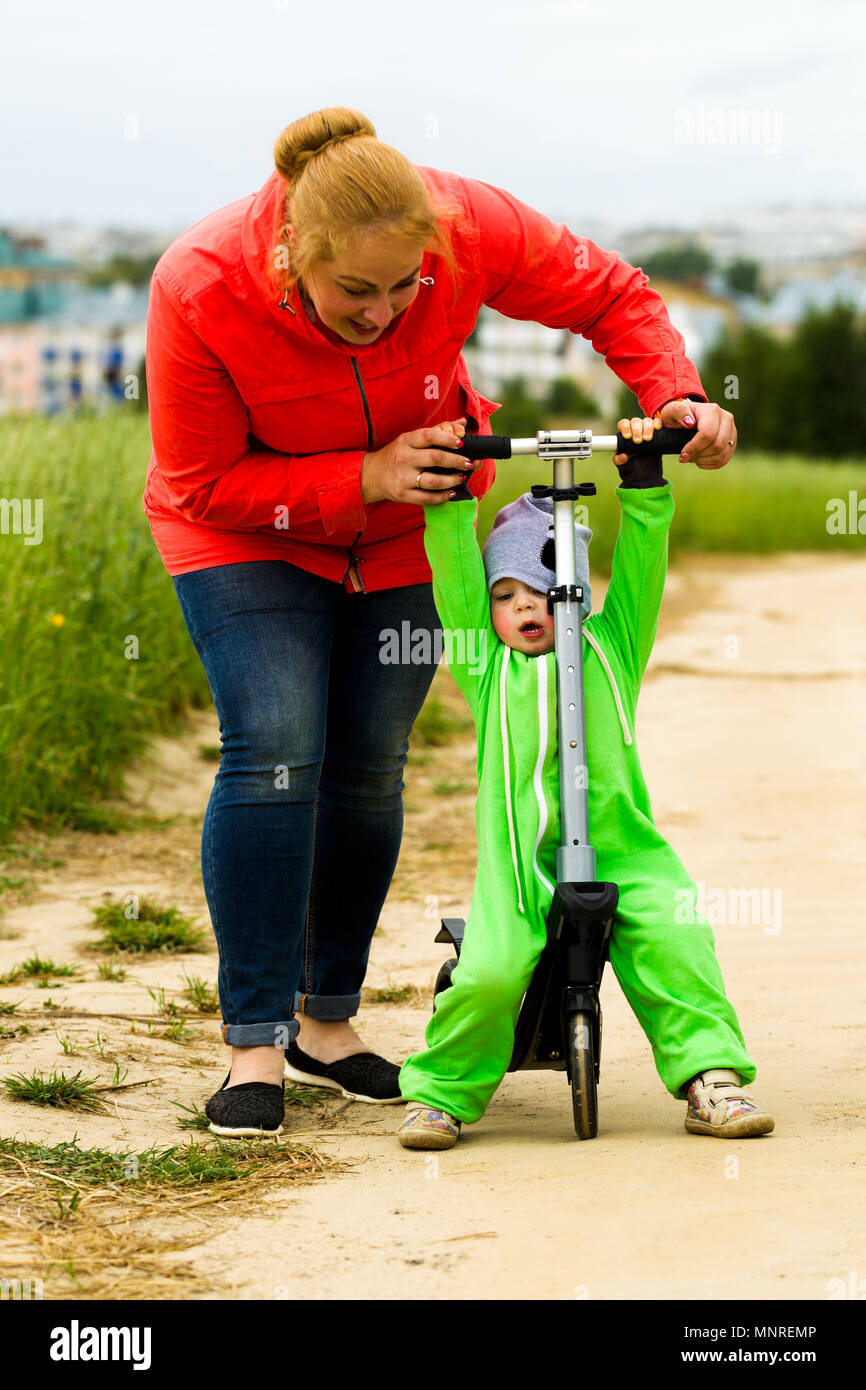 Little girl is riding a scooter with her parents Stock Photo