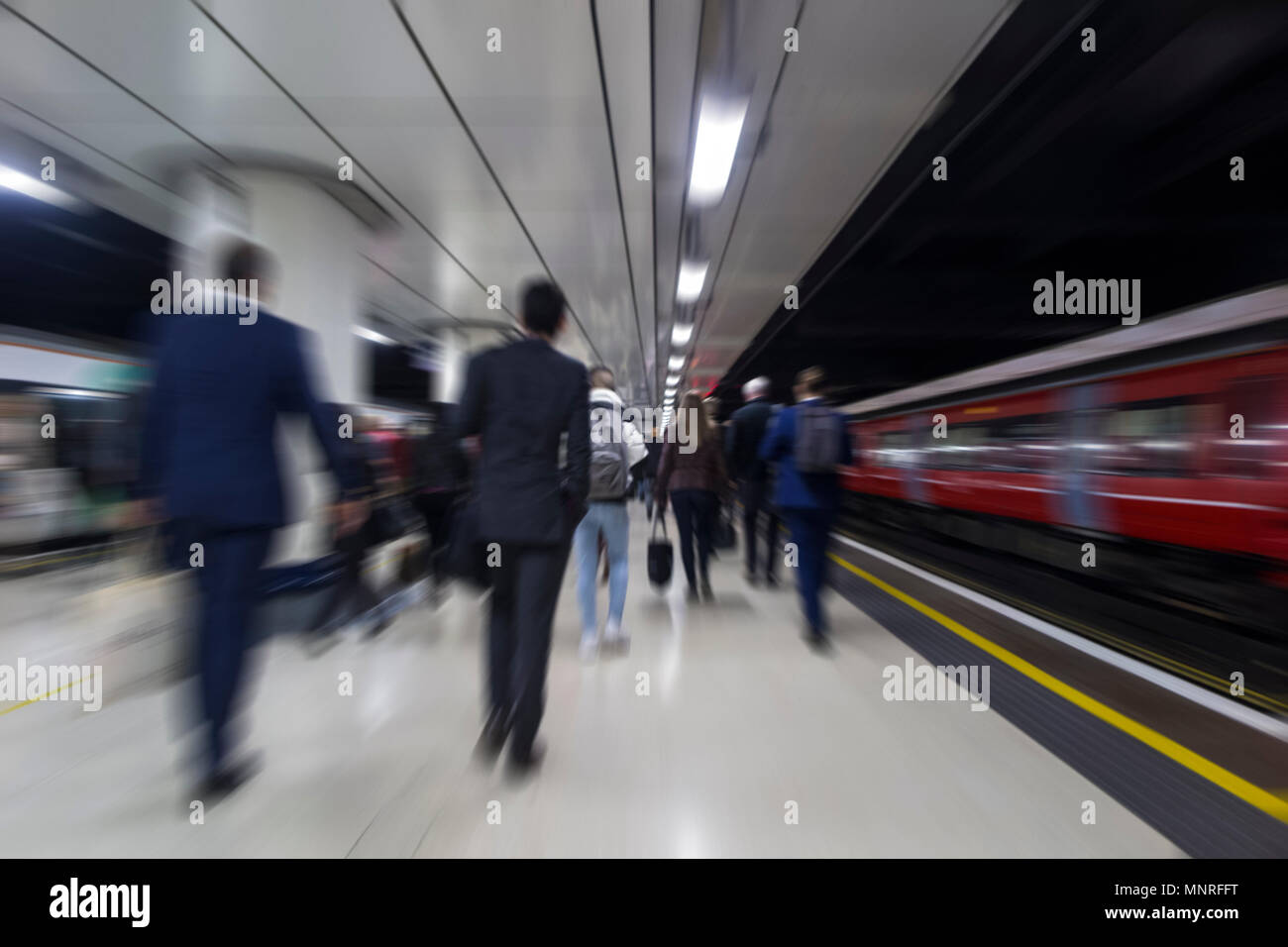 Commuters racing to work on the platform of a London station once the train pulls in Stock Photo